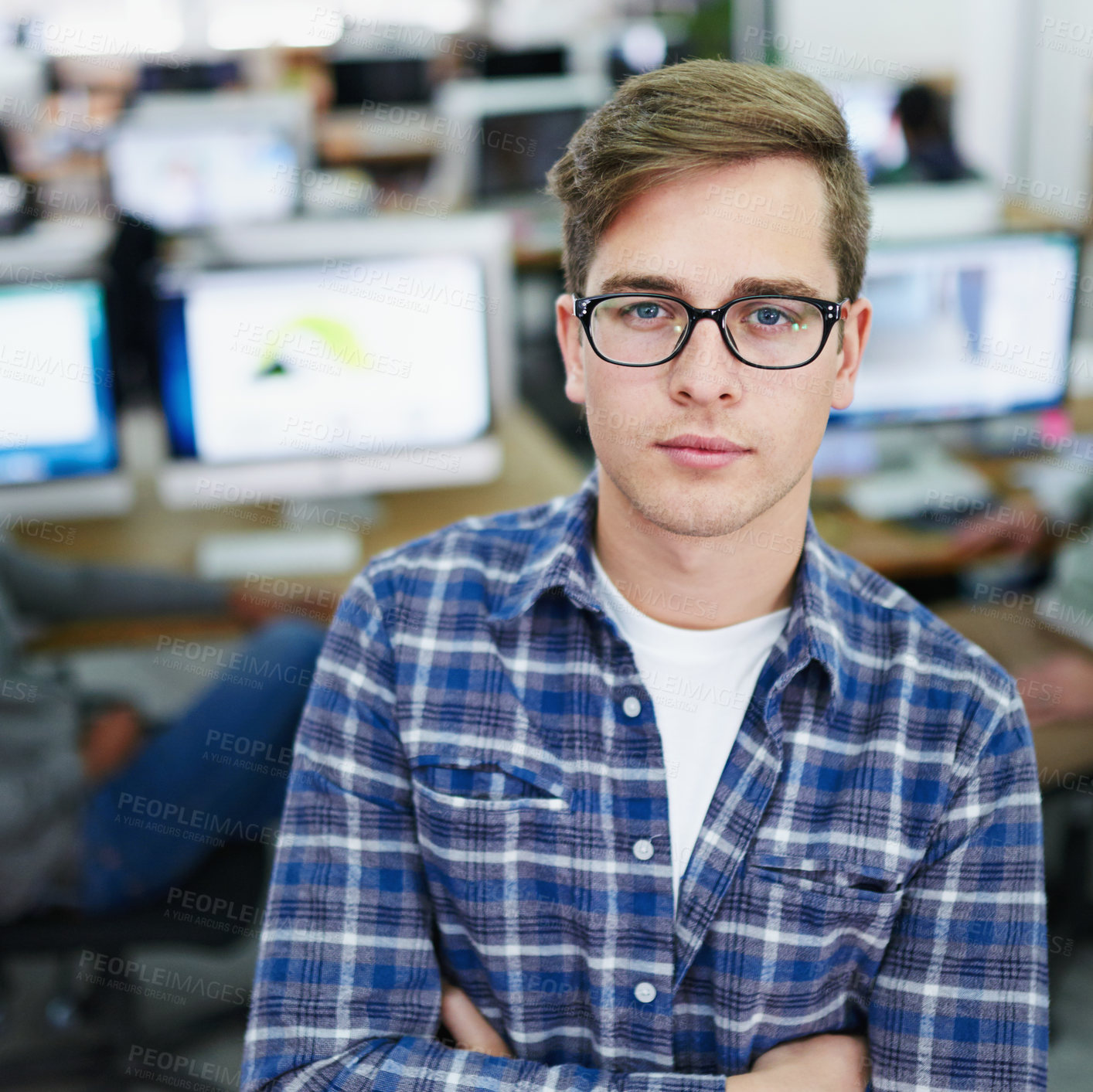 Buy stock photo Portrait of a focused young designer standing in an office with colleagues working in the background