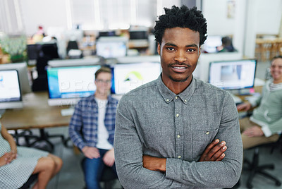 Buy stock photo Portrait of a smiling young designer standing in an office with colleagues working in the background