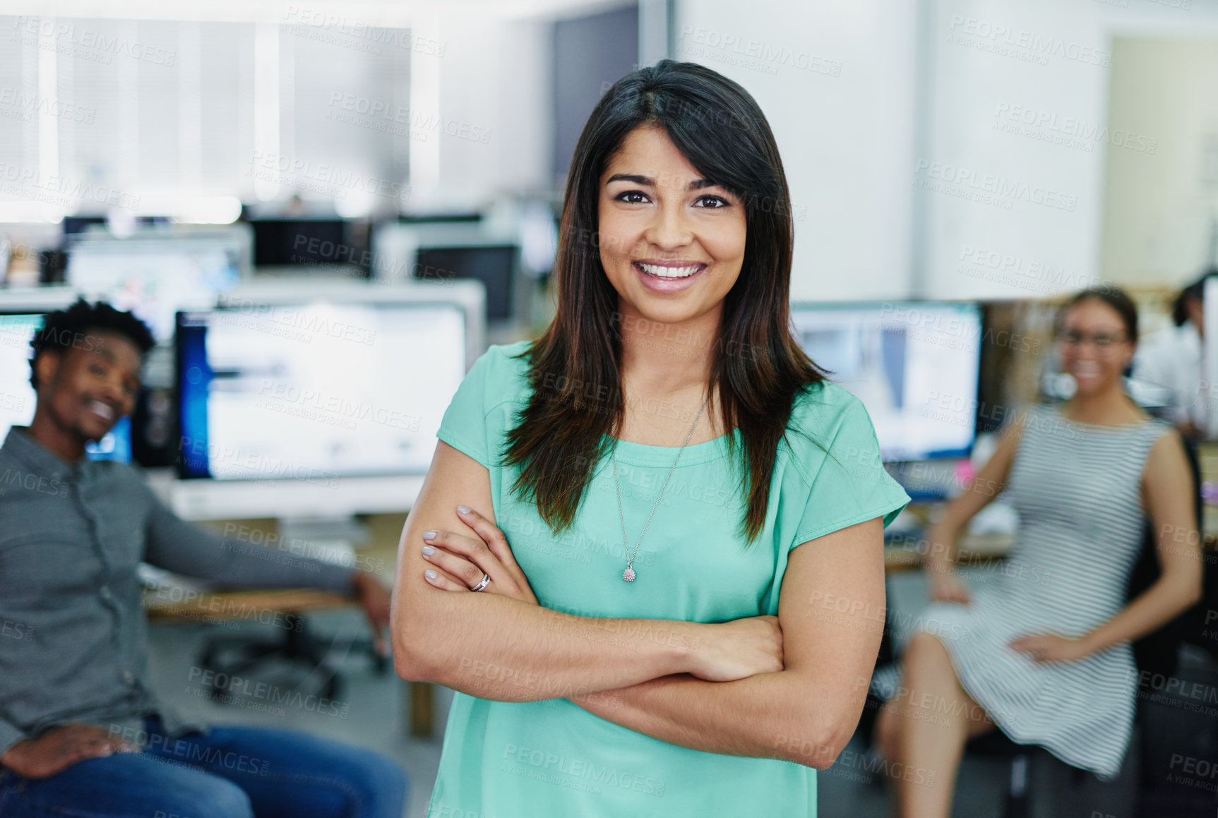 Buy stock photo Portrait of a smiling young designer standing in an office with colleagues working in the background