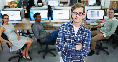 Buy stock photo Portrait of a focused young designer standing in an office with colleagues working in the background