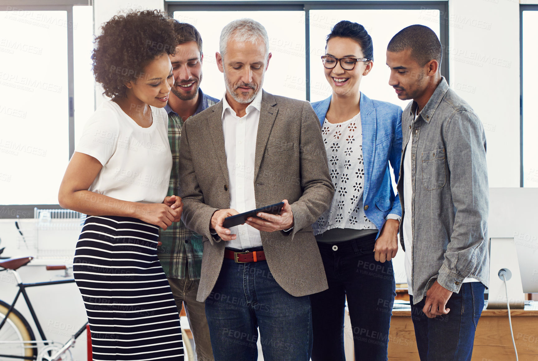 Buy stock photo Shot of a group of designers talking together over a digital tablet in an office