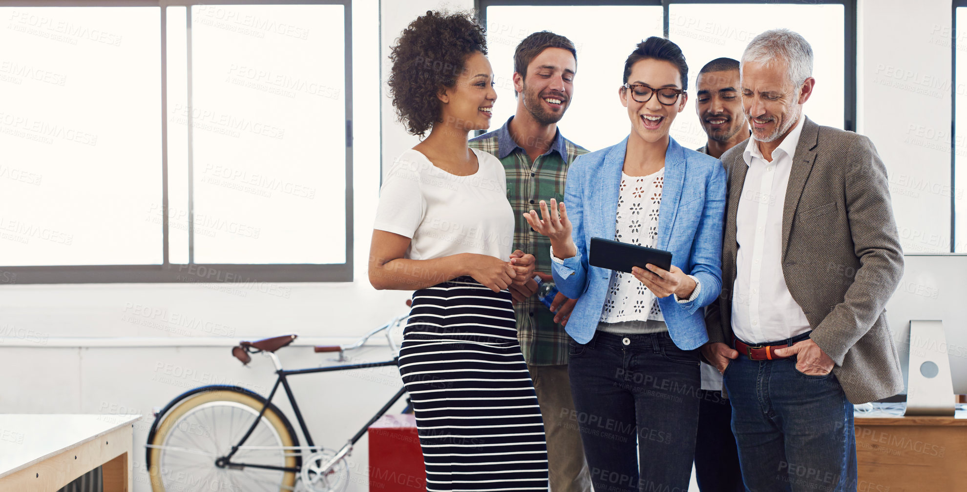 Buy stock photo Shot of a group of designers talking together over a digital tablet in an office