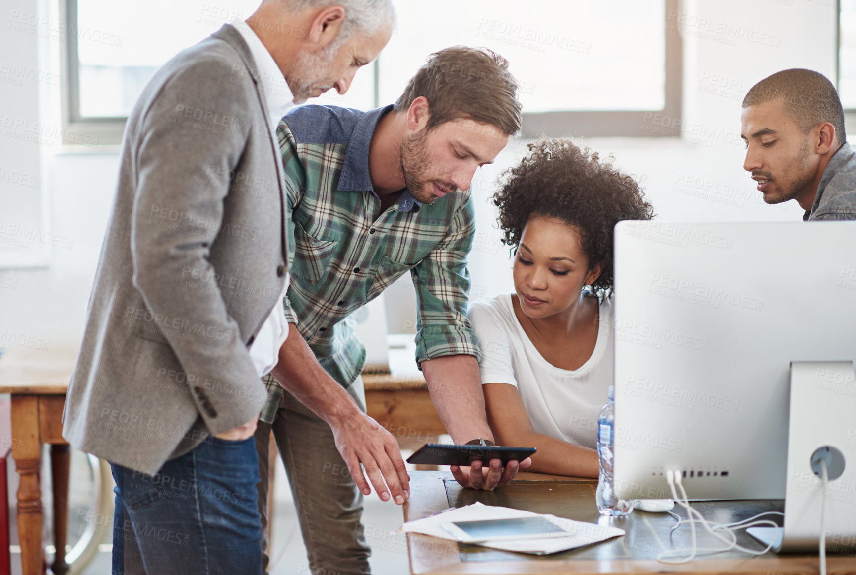 Buy stock photo Shot of a group of designers talking together over a digital tablet in an office