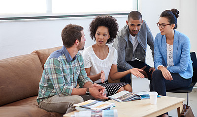 Buy stock photo Shot of a diverse group of young designers talking together while sitting on a sofa in an office