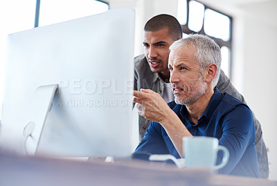Buy stock photo Shot of two designers talking together while sitting at a computer in an office