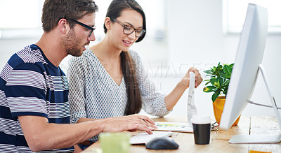 Buy stock photo Shot of two young designers talking together over a digital tablet in an office