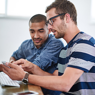 Buy stock photo Shot of two young designers talking together over a digital tablet in an office