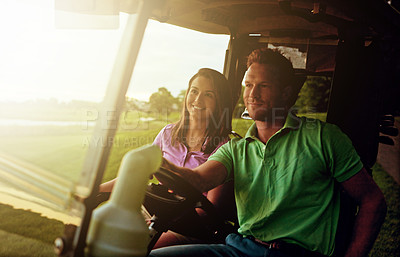 Buy stock photo Shot of a couple riding in a golf cart on a golf course