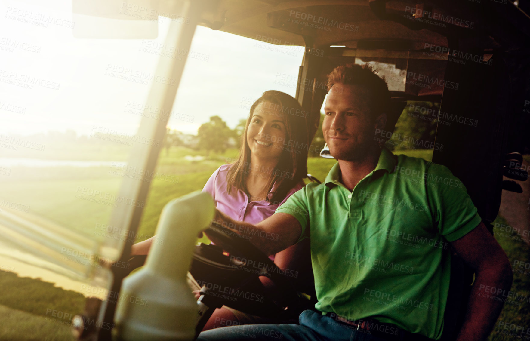 Buy stock photo Shot of a couple riding in a golf cart on a golf course