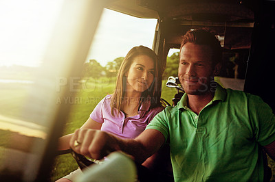 Buy stock photo Shot of a couple riding in a golf cart on a golf course