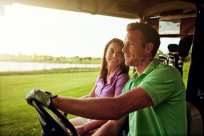 Buy stock photo Shot of a couple riding in a golf cart on a golf course