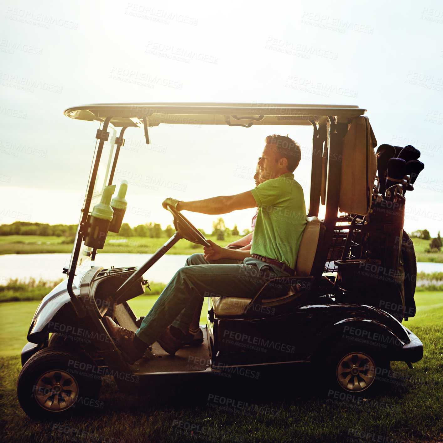 Buy stock photo Shot of a couple riding in a golf cart on a golf course