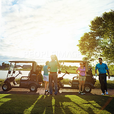 Buy stock photo Shot of a group of friends playing a round of golf on a fairway
