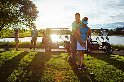 Buy stock photo Shot of a husband helping his wife play golf