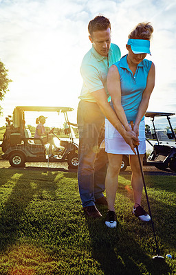 Buy stock photo Shot of a husband helping his wife play golf