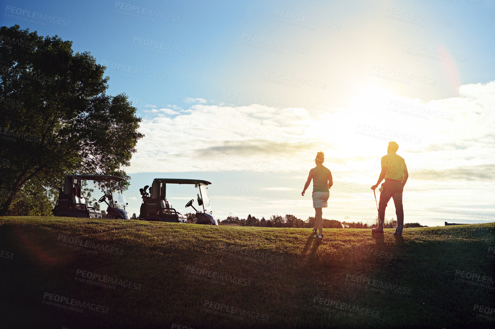 Buy stock photo Shot of a couple walking back to their golf cart on the fairway