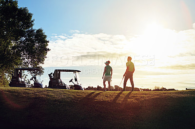 Buy stock photo Shot of a couple walking back to their golf cart on the fairway