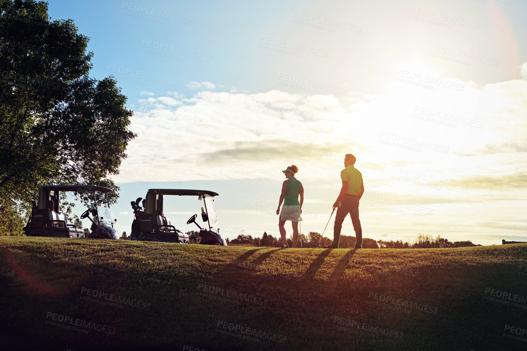 Buy stock photo Shot of a couple walking back to their golf cart on the fairway