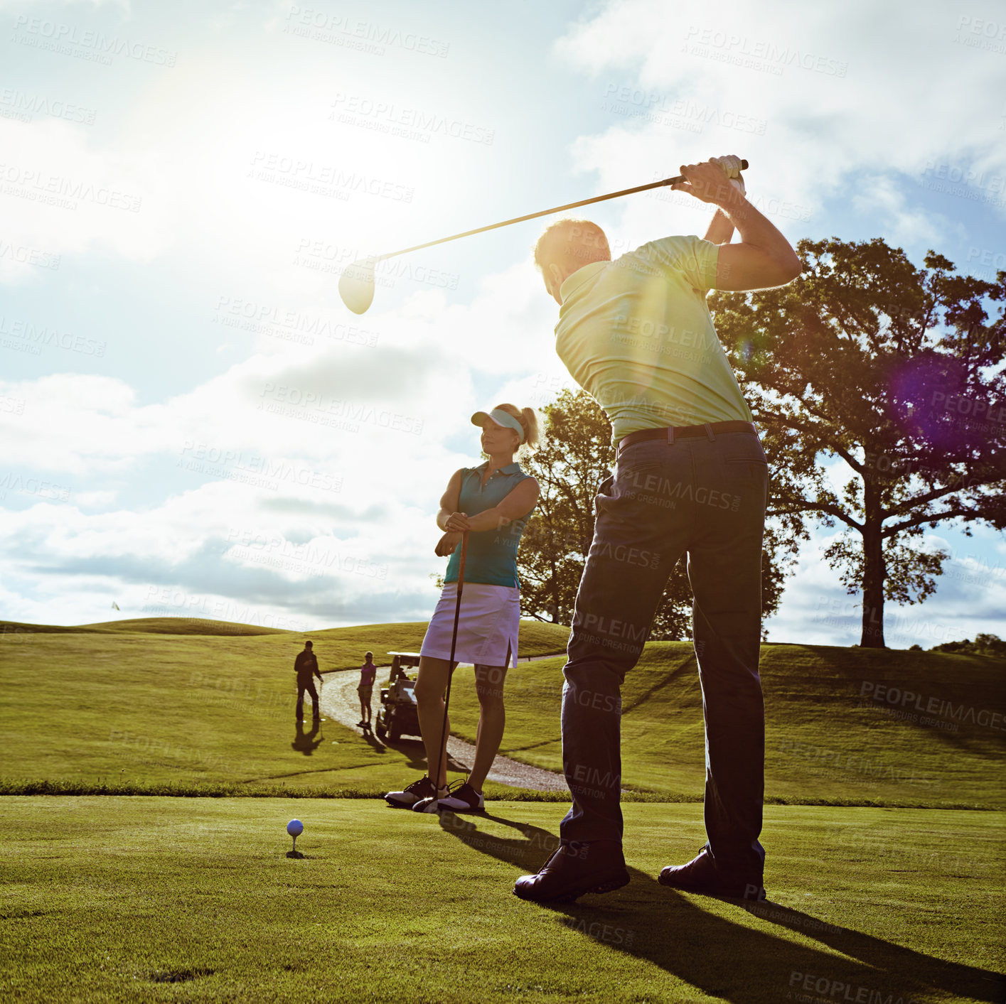Buy stock photo Man, driver and swing with tee off at golf course, sky and space for bonding with training on grass. People, couple and partner in summer with club, fitness challenge or ball for sports game on green