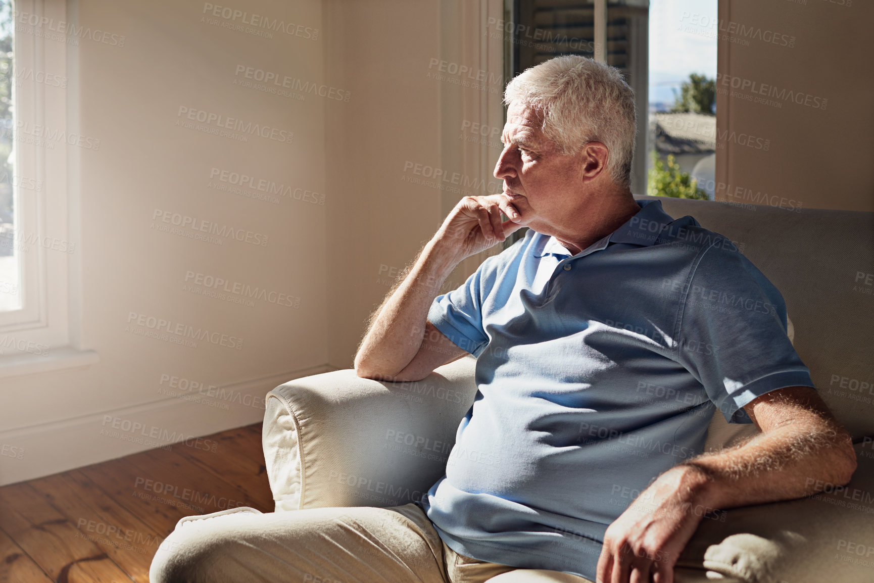 Buy stock photo Shot of a pensive senior man sitting in a chair at home alone