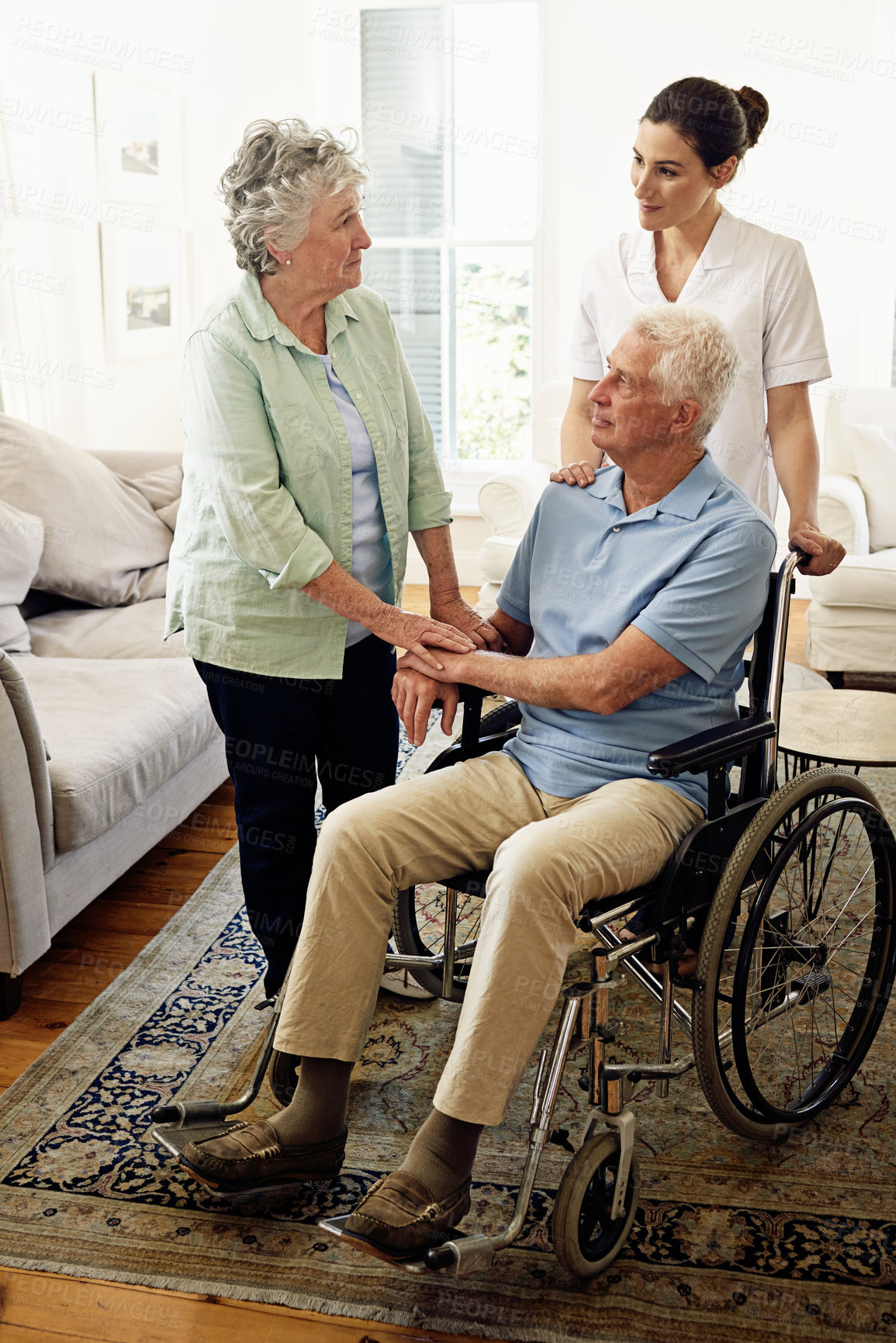 Buy stock photo Support, old man in wheelchair with wife and nurse at nursing home for help with disability and rehabilitation. Healthcare, disability and senior couple with caregiver in living room for elderly care