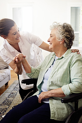 Buy stock photo Shot of a smiling caregiver helping a senior woman in a wheelchair at home