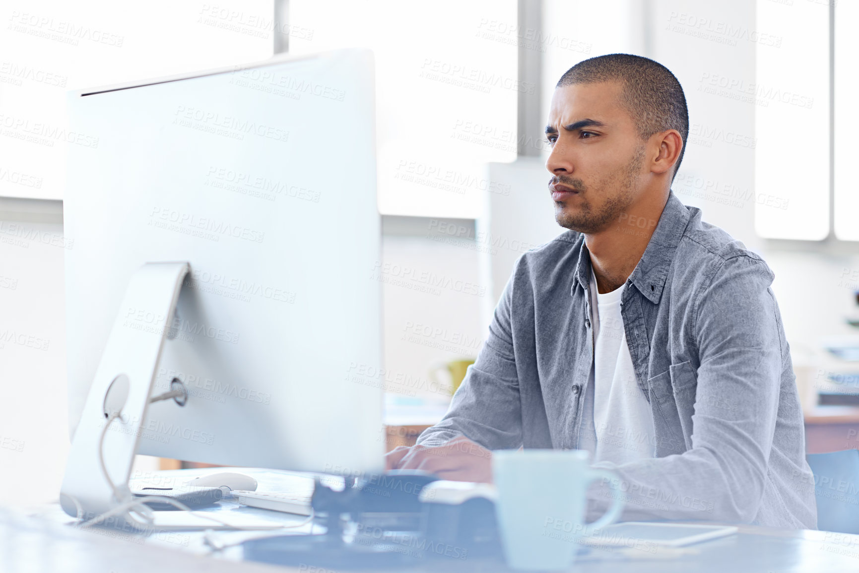 Buy stock photo Shot of a young designer working on a computer at a desk in an office