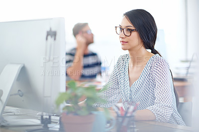 Buy stock photo Shot of a young designer working on a computer at a desk in an office