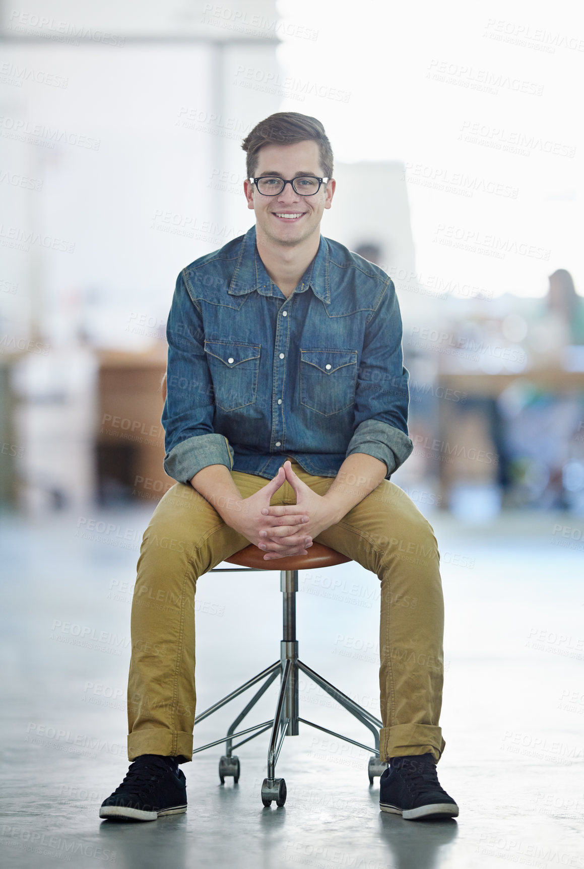 Buy stock photo Portrait of a smiling young designer sitting on a chair in a large office
