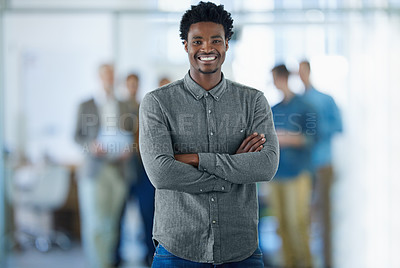 Buy stock photo Portrait of a smiling young man standing in an office with colleagues in the background