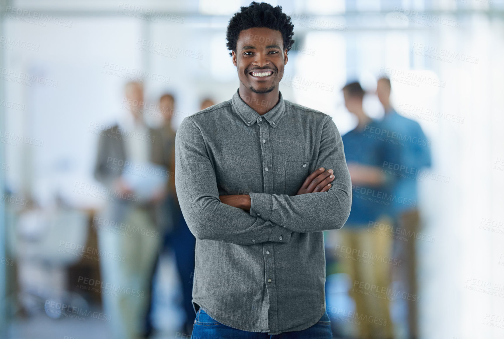 Buy stock photo Portrait of a smiling young man standing in an office with colleagues in the background