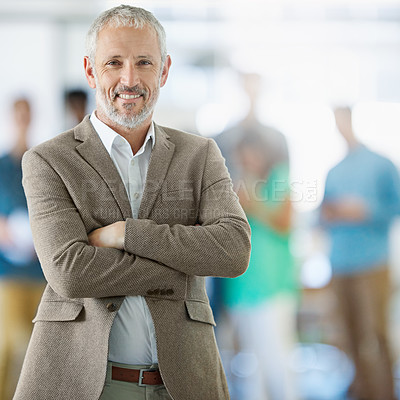Buy stock photo Portrait of a smiling mature man standing in an office with colleagues in the background