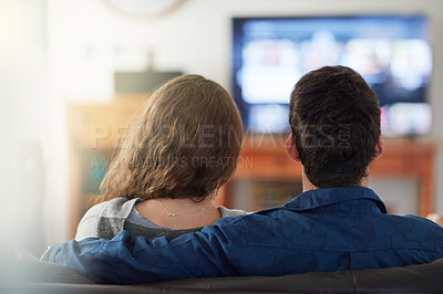 Buy stock photo Rearview shot of a relaxed young couple watching tv at home