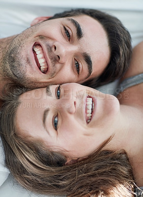 Buy stock photo Portrait of a happy young couple relaxing together on a bed at home