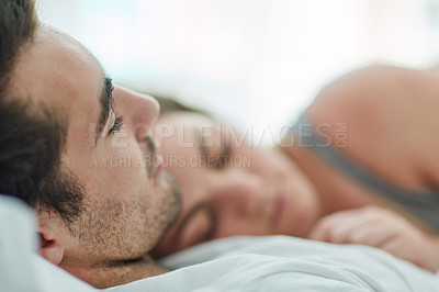 Buy stock photo Shot of a relaxed young couple sleeping in bed together at home