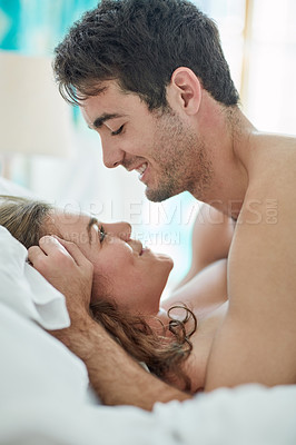 Buy stock photo Shot of a young couple sharing an intimate moment in bed