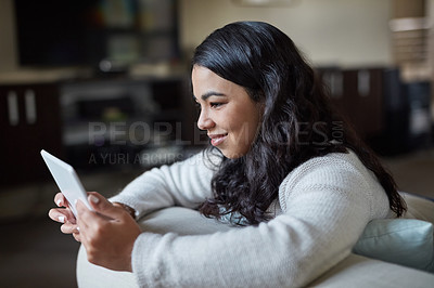Buy stock photo Shot of an attractive young woman using a digital tablet at home