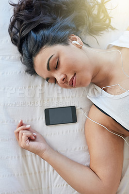 Buy stock photo Shot of an attractive young woman listening to music while lying down on her bed at home