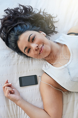 Buy stock photo Portrait of an attractive young woman listening to music while lying down on her bed at home