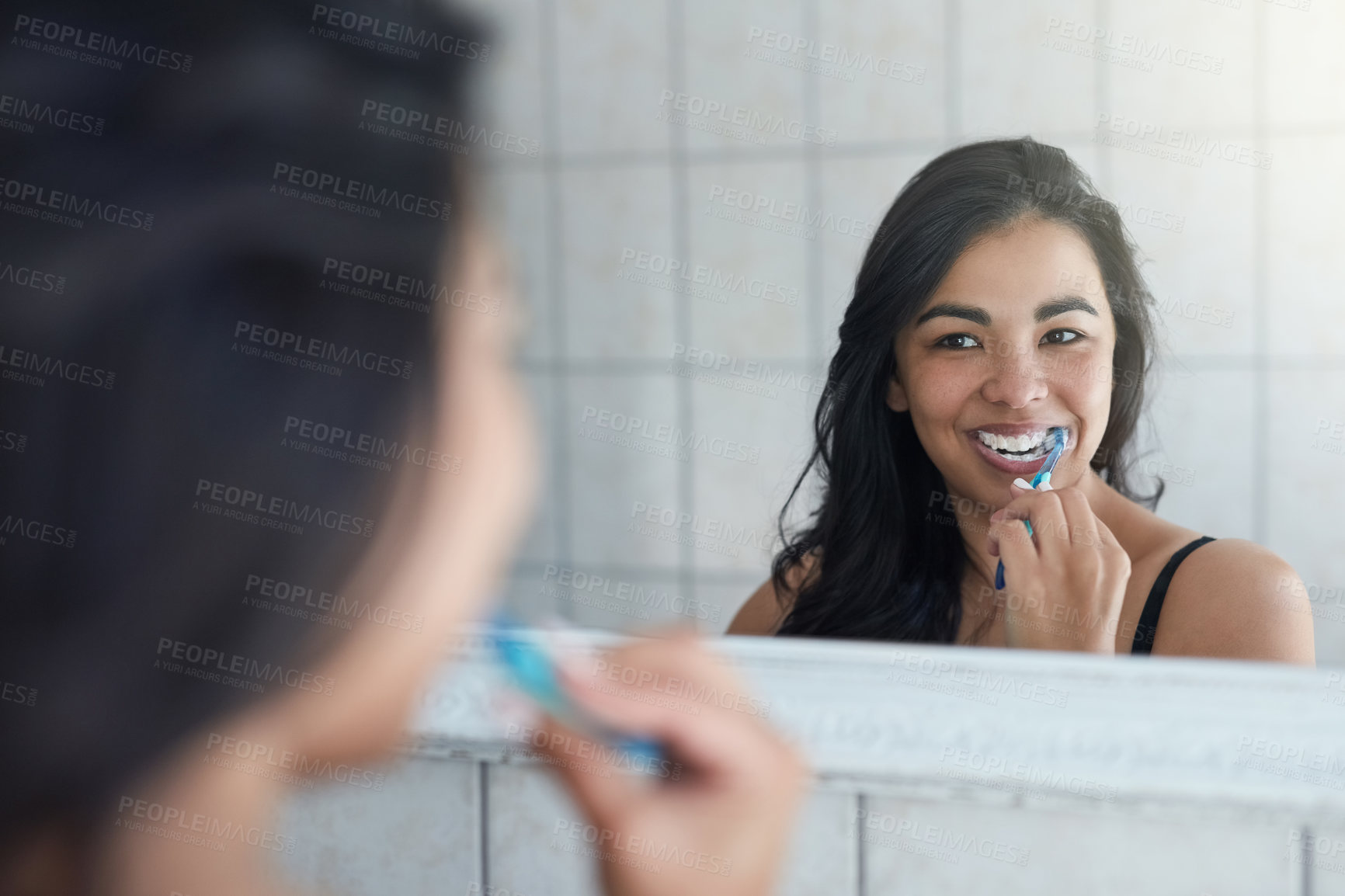 Buy stock photo Shot of an attractive young woman brushing her teeth in the bathroom