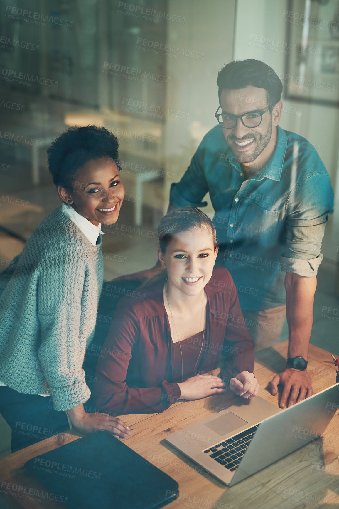 Buy stock photo High angle portrait of three young businesspeople looking at a laptop