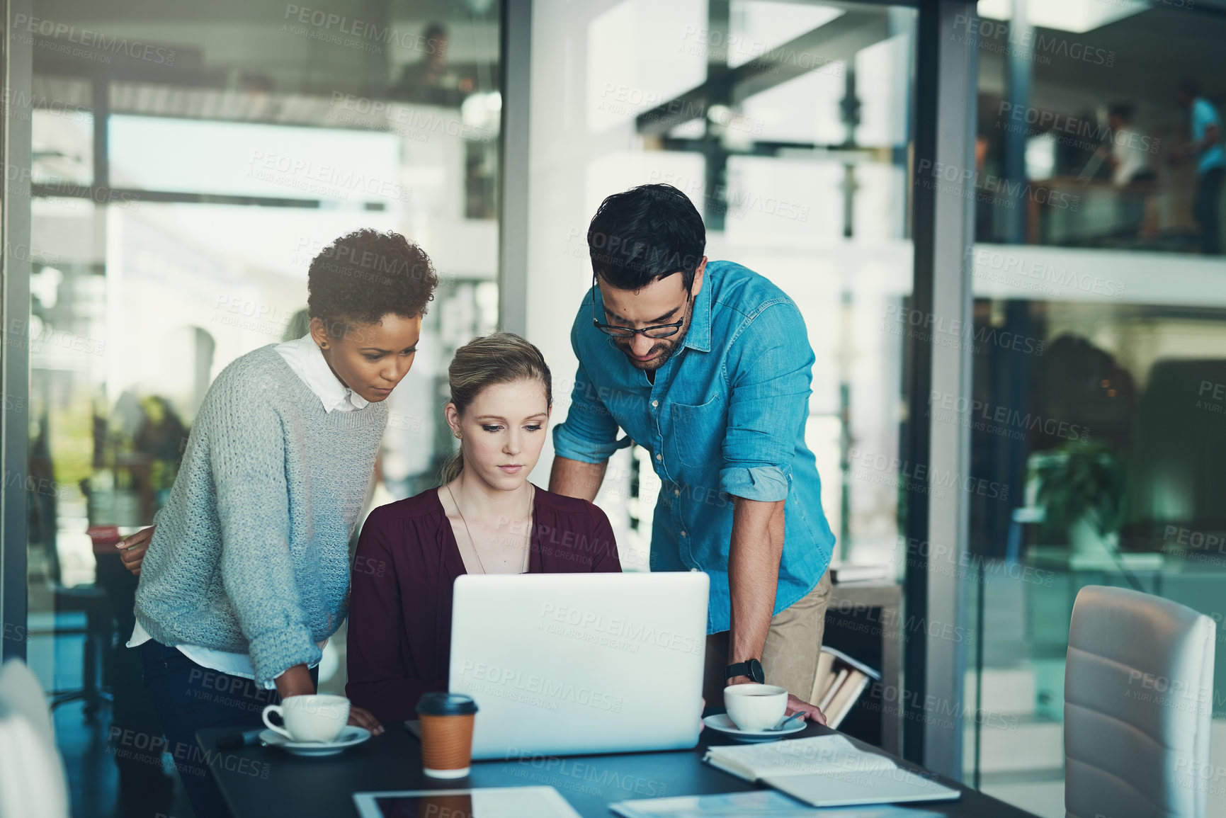 Buy stock photo Cropped shot of three businesspeople gathered around a laptop in the office