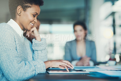 Buy stock photo Shot of a young businesswoman using her tablet during a meeting