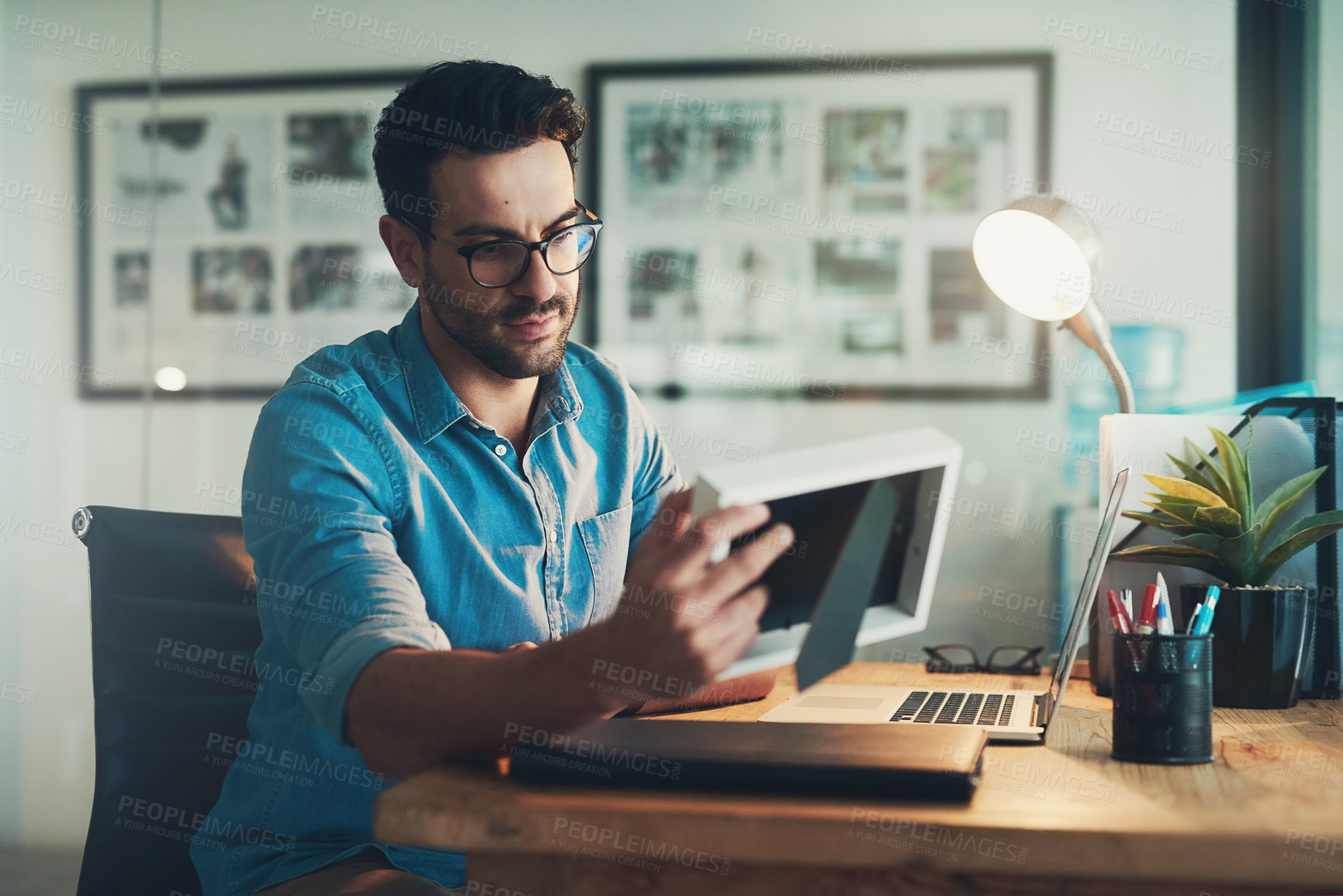 Buy stock photo Shot of a young businessman looking at a photo frame while working in his office