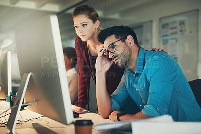 Buy stock photo Shot of two young businesspeople looking stressed while working on a computer in the office