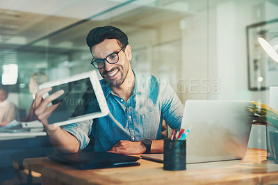 Buy stock photo Shot of a young businessman looking at a photo frame while working in his office