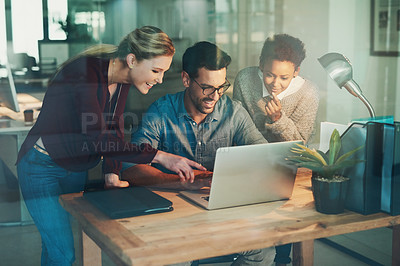 Buy stock photo High angle shot of three young businesspeople looking at a laptop