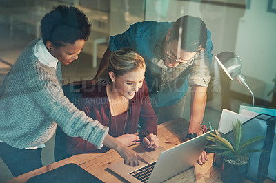 Buy stock photo High angle shot of three young businesspeople looking at a laptop