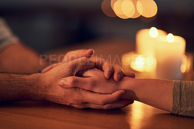 Buy stock photo Closeup of two unrecognizable people holding hands over a dinner table with candle light in the background