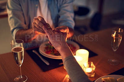 Buy stock photo Cropped shot of an unrecognizable man proposing to his wife over a candle lit dinner at night
